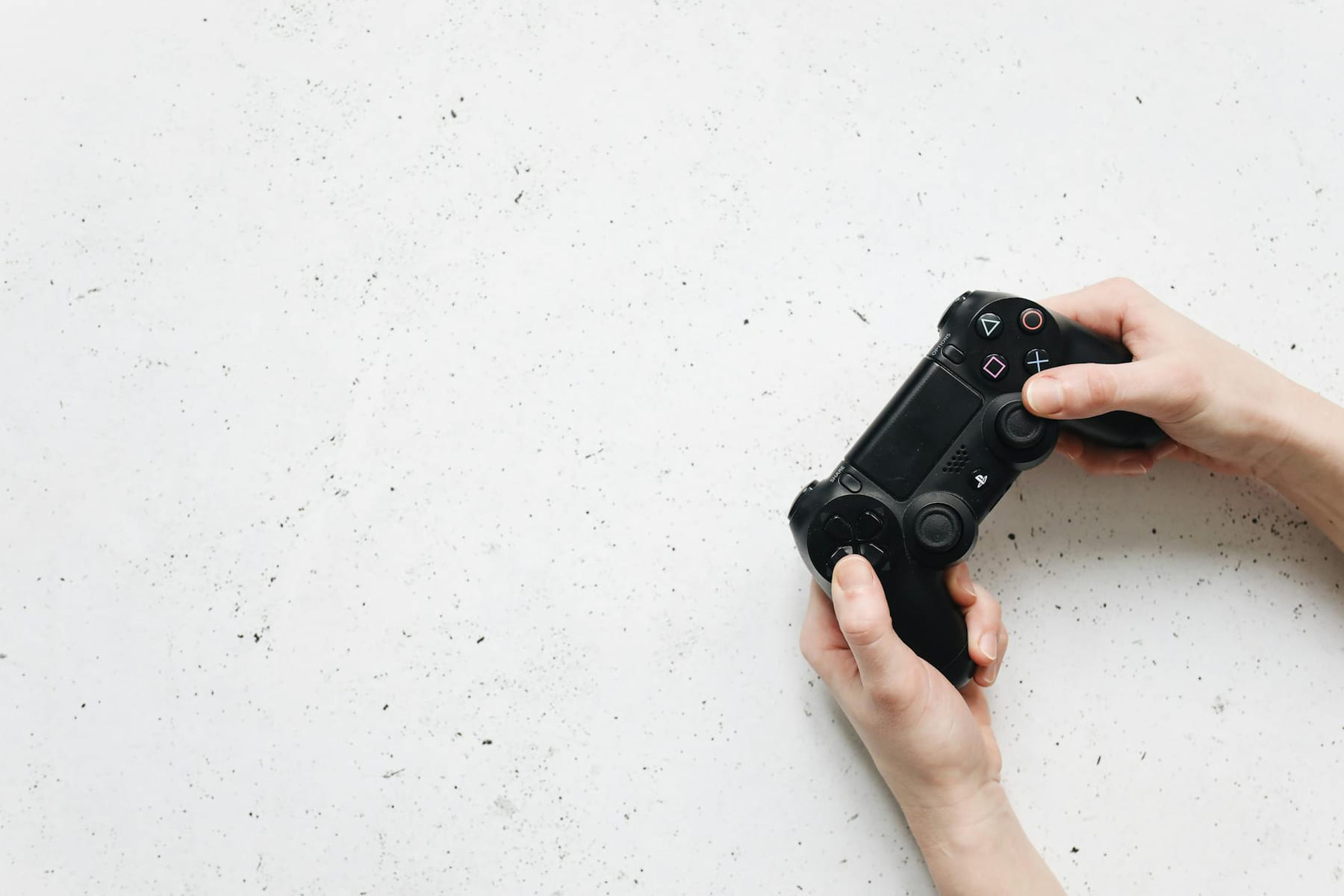 Close-up of hands holding a black game controller on a white background. on The Loading Screen