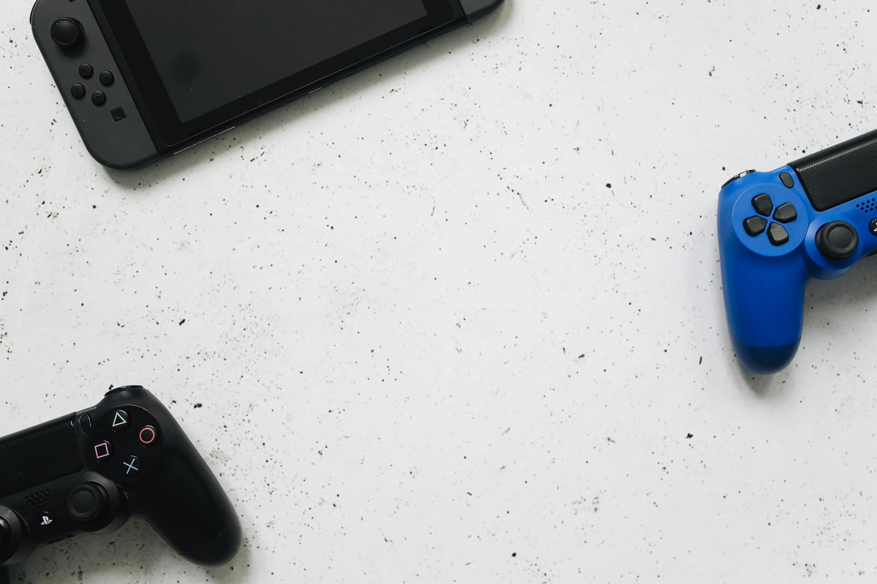 A flat lay of gaming consoles and controllers on a white surface, ideal for tech enthusiasts. on The Loading Screen