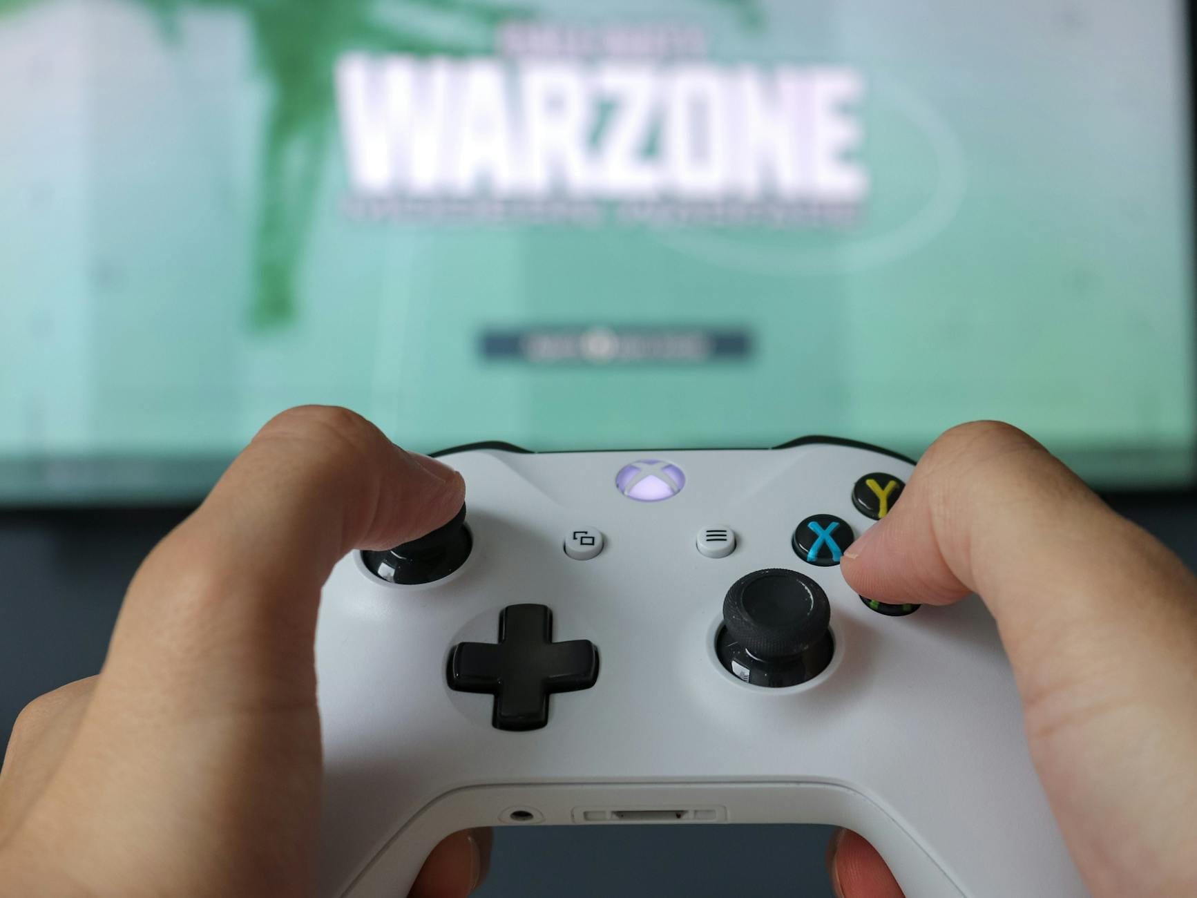 A close-up of hands holding an Xbox controller against a game screen, highlighting the gaming experience. on The Loading Screen