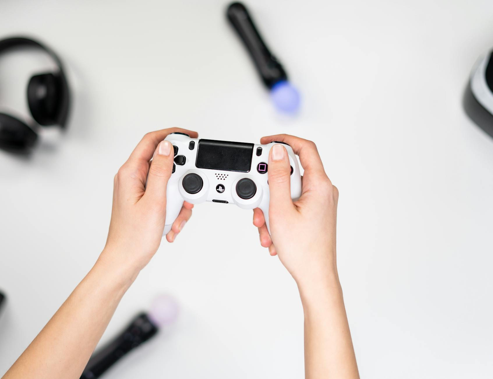 Hands holding a game controller surrounded by gaming accessories on a white background. on The Loading Screen