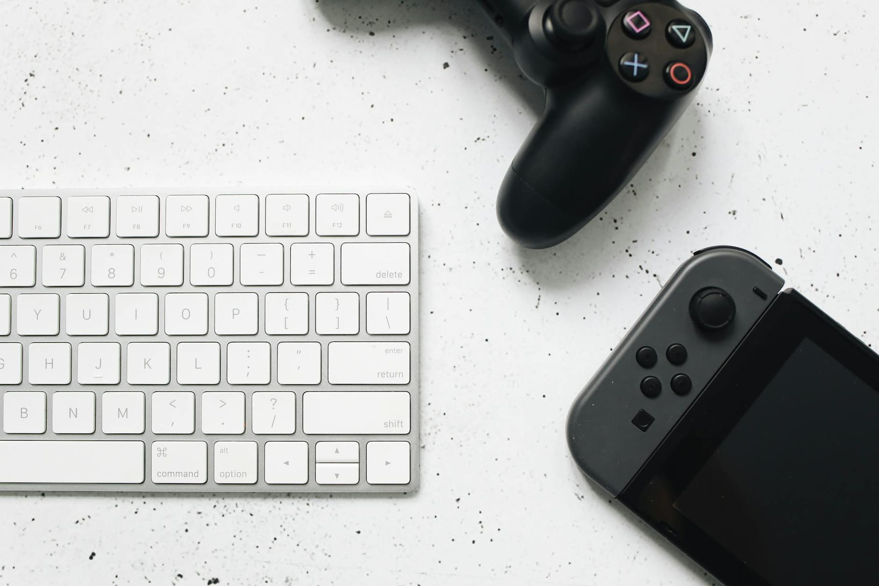 Close-up of a wireless keyboard and gaming controllers on a marble surface. on The Loading Screen