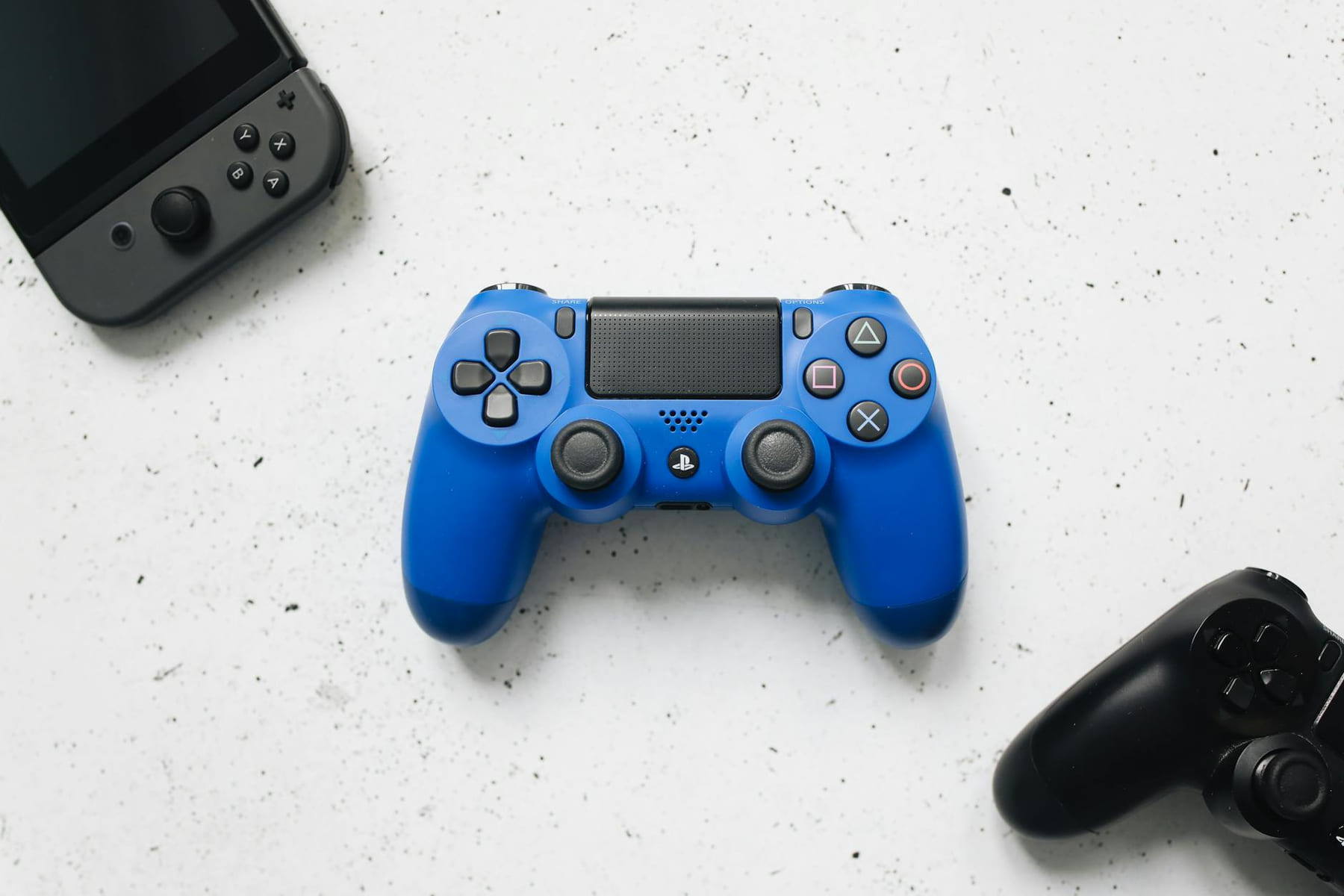 A top view of various colorful gaming controllers on a white surface. on The Loading Screen