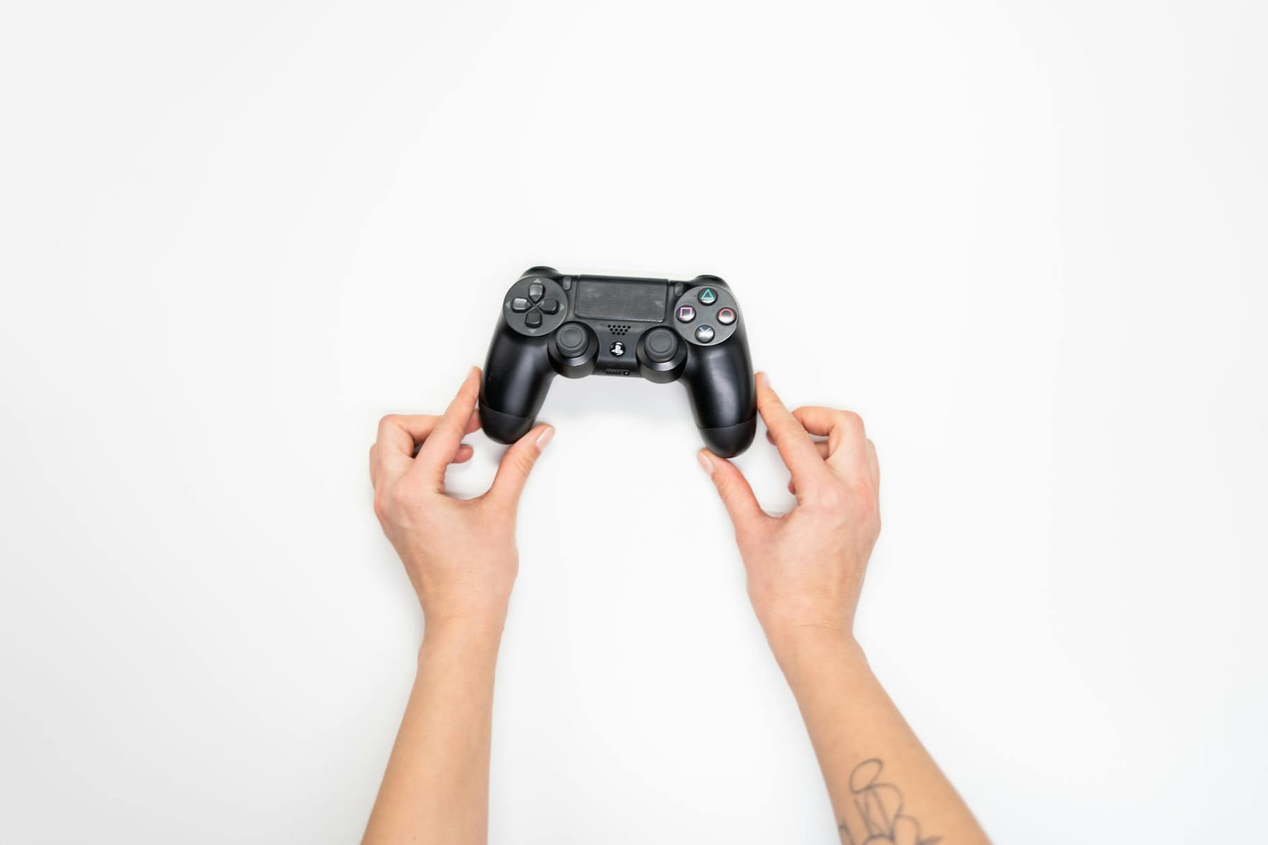 Top view of hands holding a black gaming controller against a white background. on The Loading Screen