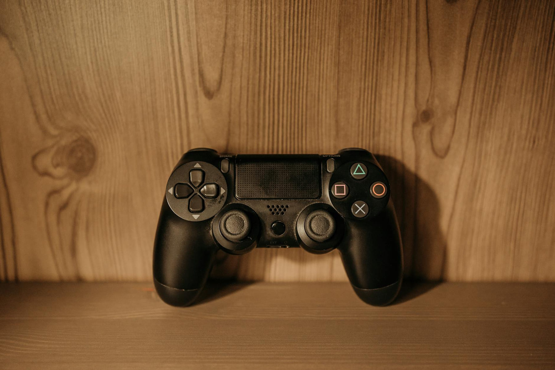 Close-up view of a black PlayStation controller placed on a wooden surface. on The Loading Screen