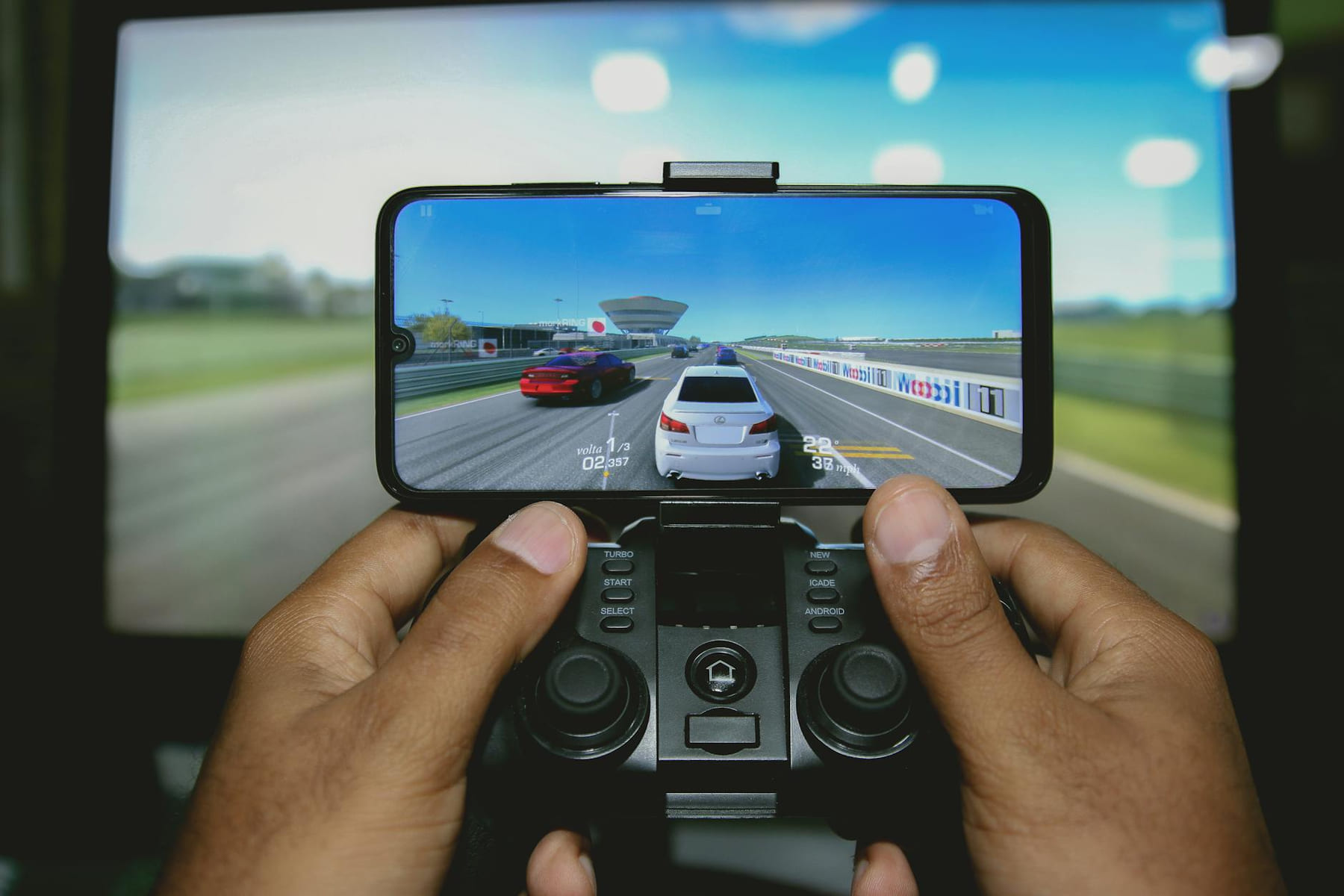 Close-up of hands playing a racing game on a mobile device with a controller. on The Loading Screen