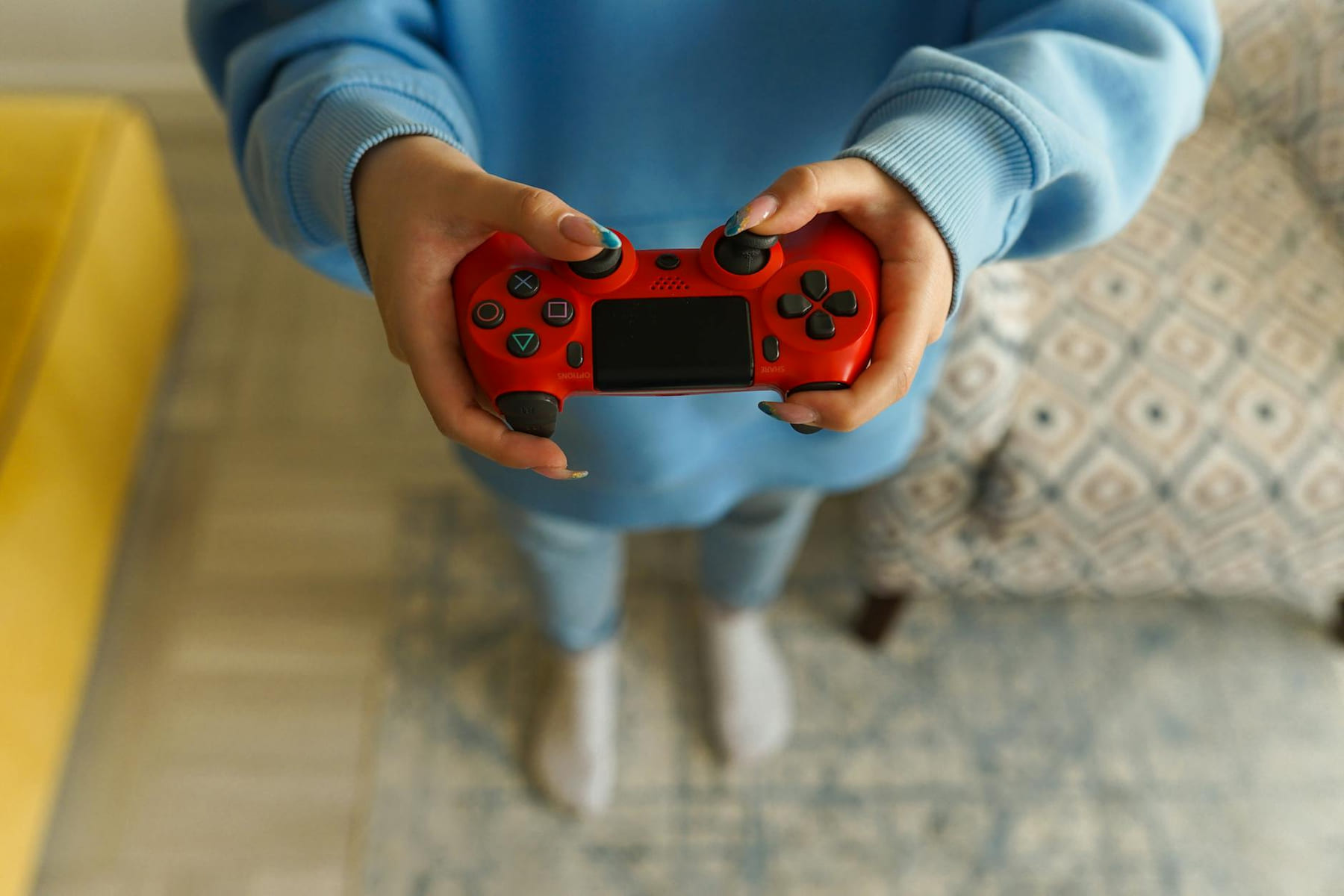 Person holding a bright red gaming controller indoors, focusing on gameplay. on The Loading Screen