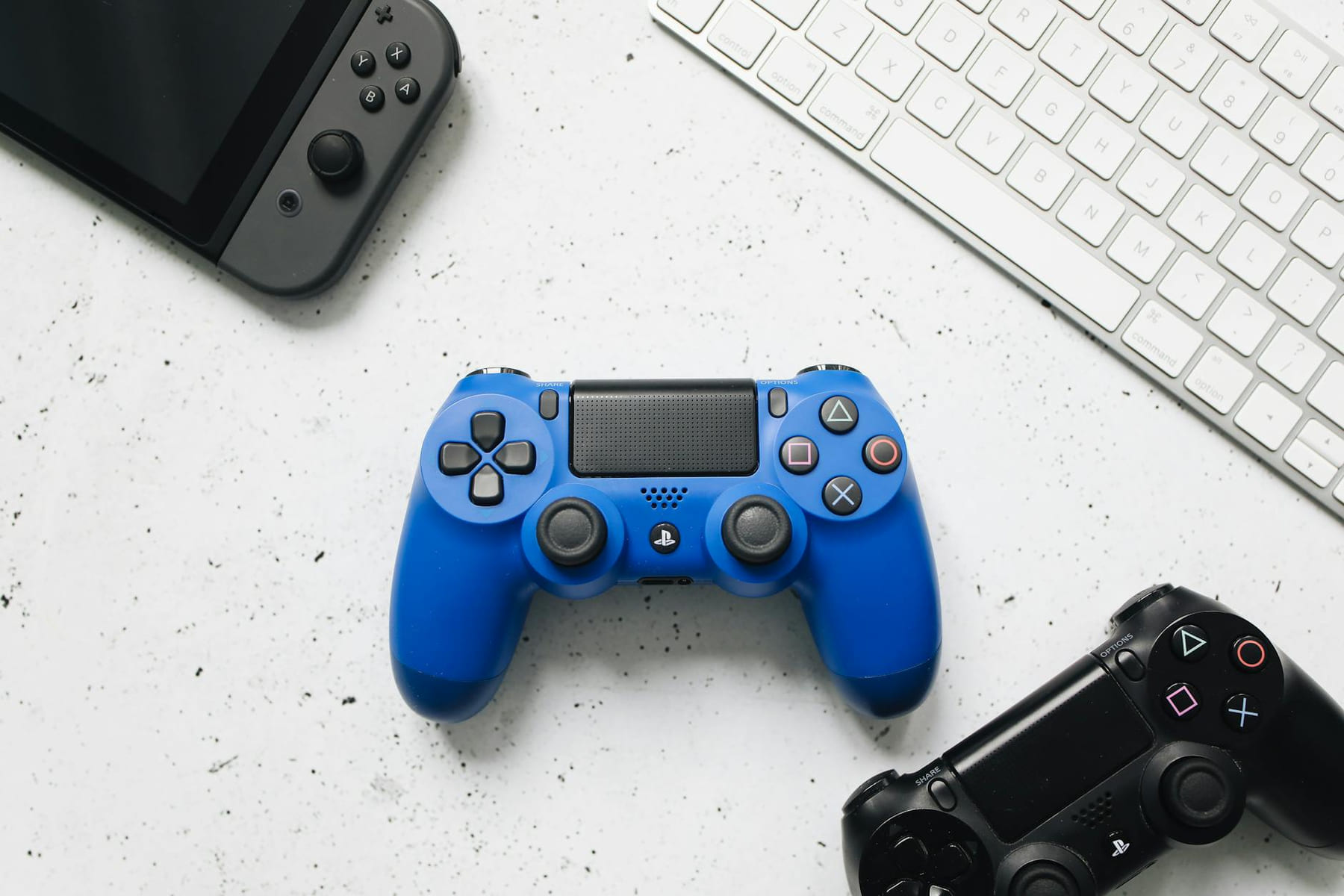Top view of various gaming controllers and a keyboard on a white surface. on The Loading Screen